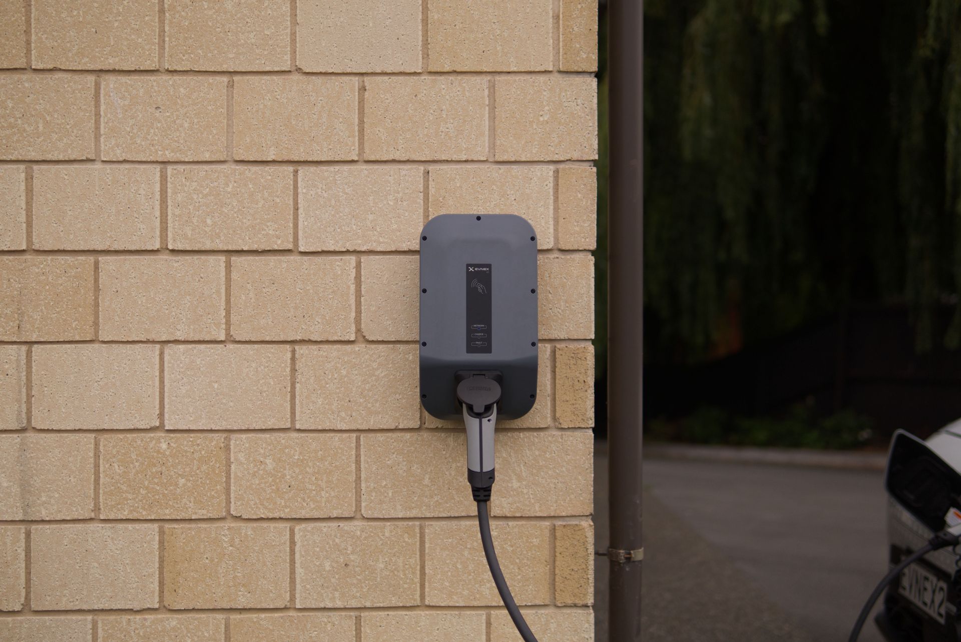 A wall-mounted electric vehicle charging station installed on a brick wall in Christchurch, New Zealand.